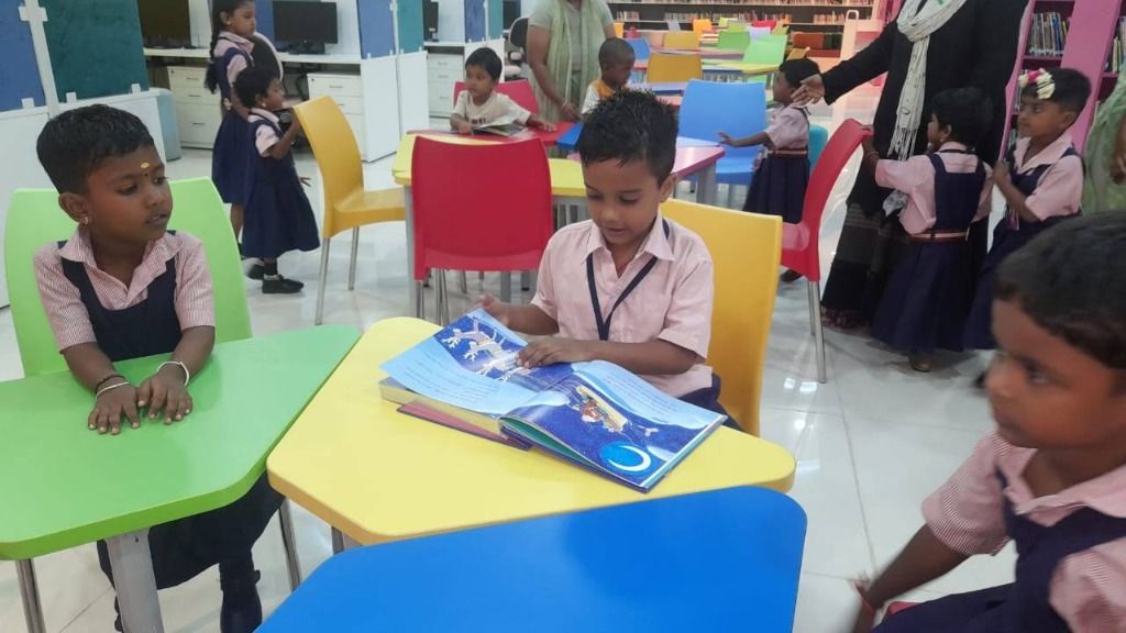 A boy turning the pages of a picture book at a bright yellow table in the school library